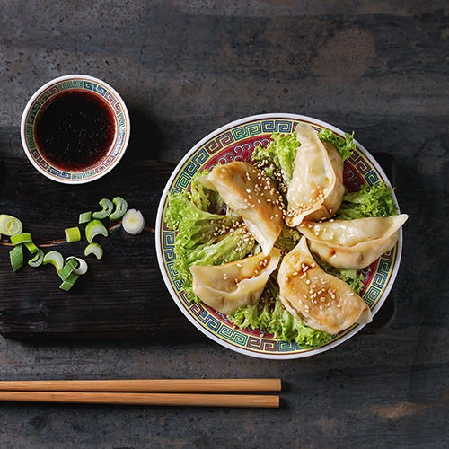 Plate of gyoza potsticker with bowl of soy sauce and chopsticks